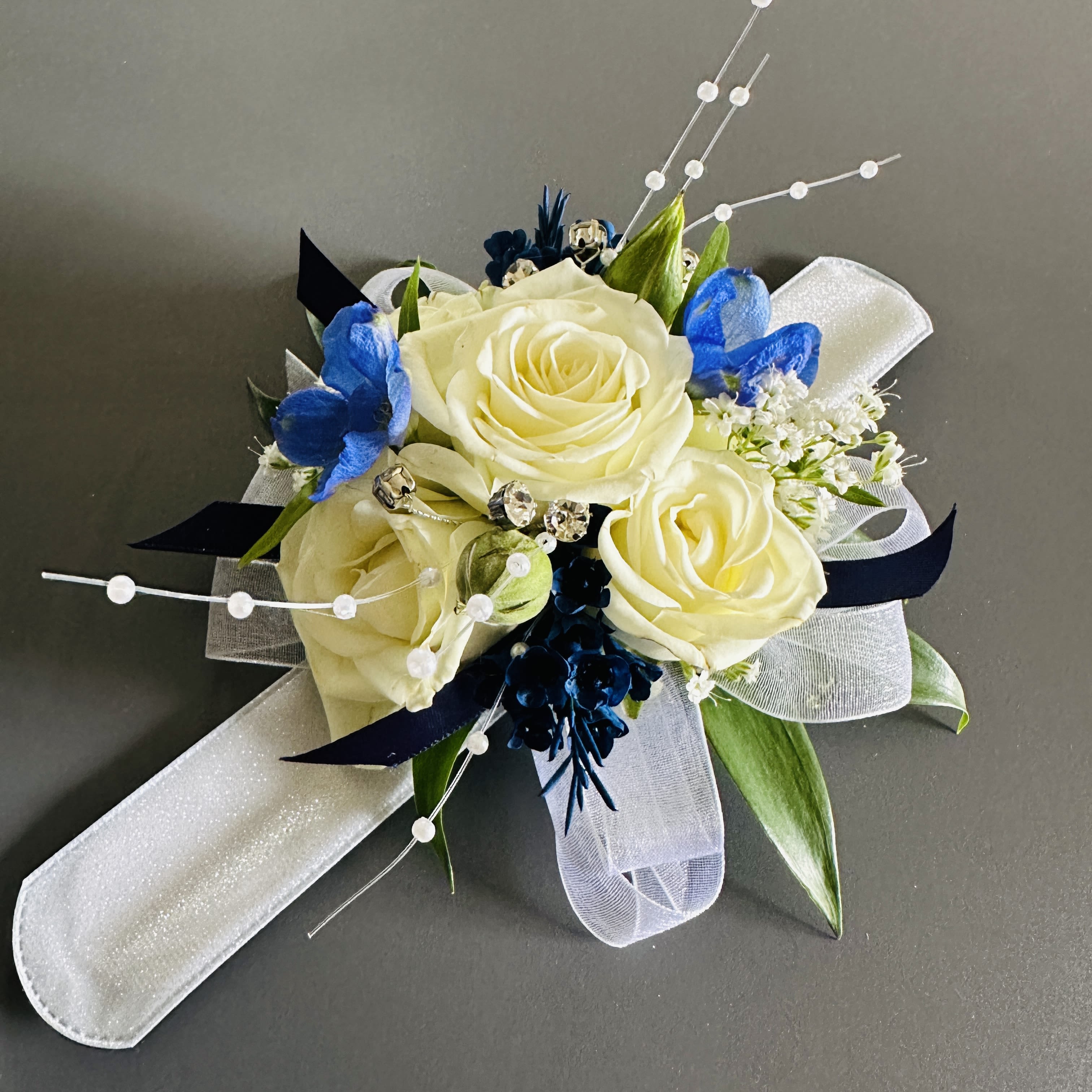 White rose corsage with blue accents and white ribbon