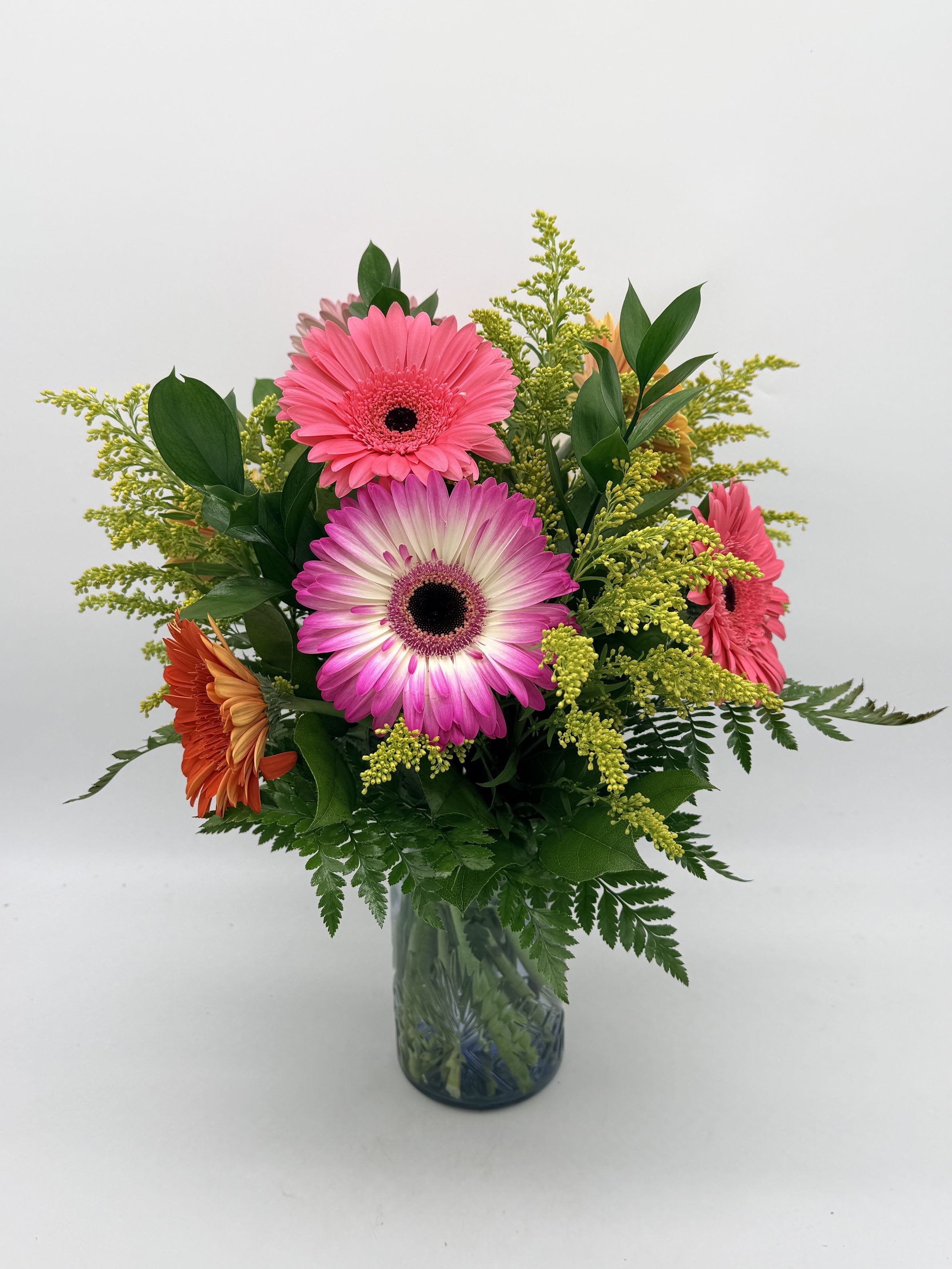 Sweet Gerbera Splash - A joyful bouquet featuring vibrant gerbera daisies accented with snapdragons and greenery. Arranged in a blue vase for a fun splash of color that feels bright, happy, and uplifting.   Gerbera colors and filler flowers may vary based on seasonal availability.