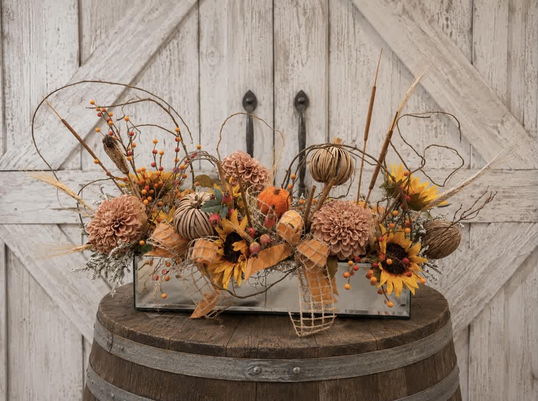 Autumn floral arrangement in a rectangular glass vase with pumpkins and sunflowers
