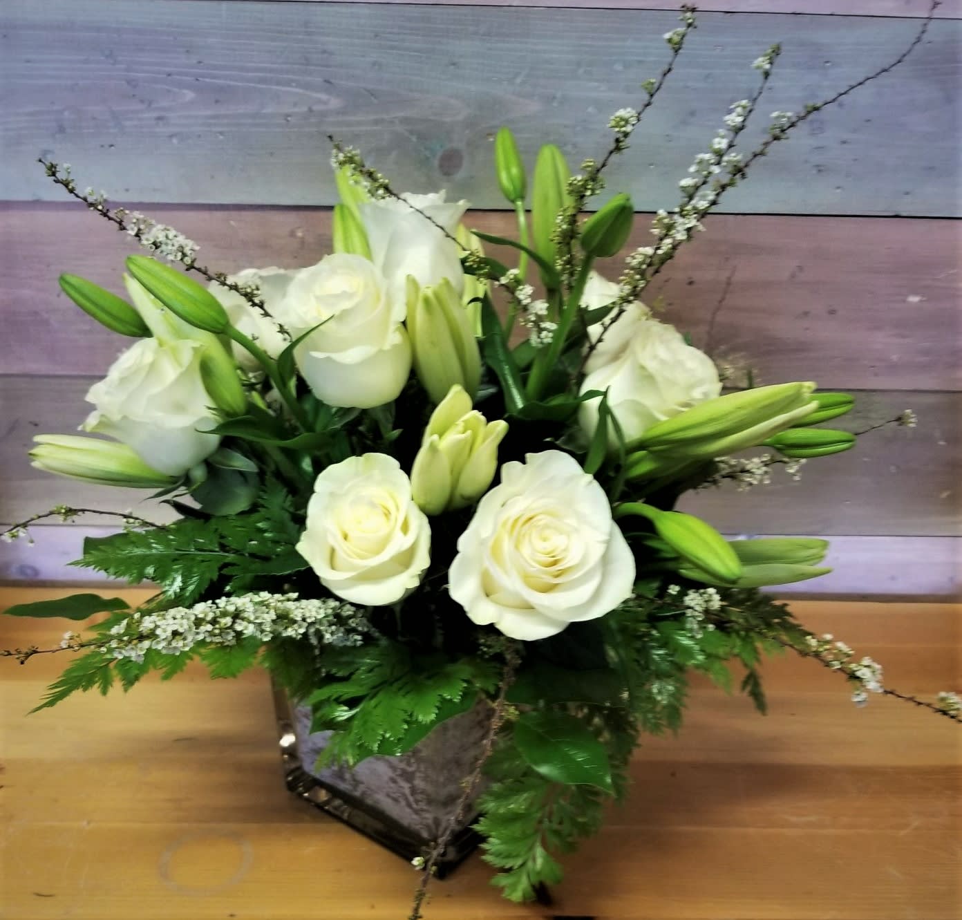 White roses and lilies arranged in a square vase