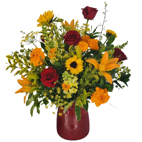 Mixed bouquet of red roses, orange lilies, and yellow flowers in a red vase