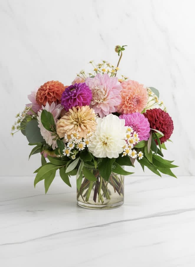 Mixed bouquet of colorful dahlias in a clear glass vase