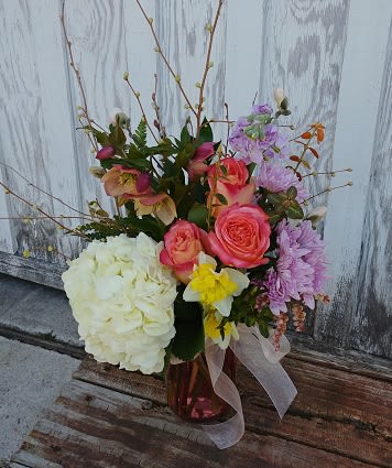 Mixed bouquet with roses, hydrangea, and daffodils in a glass vase