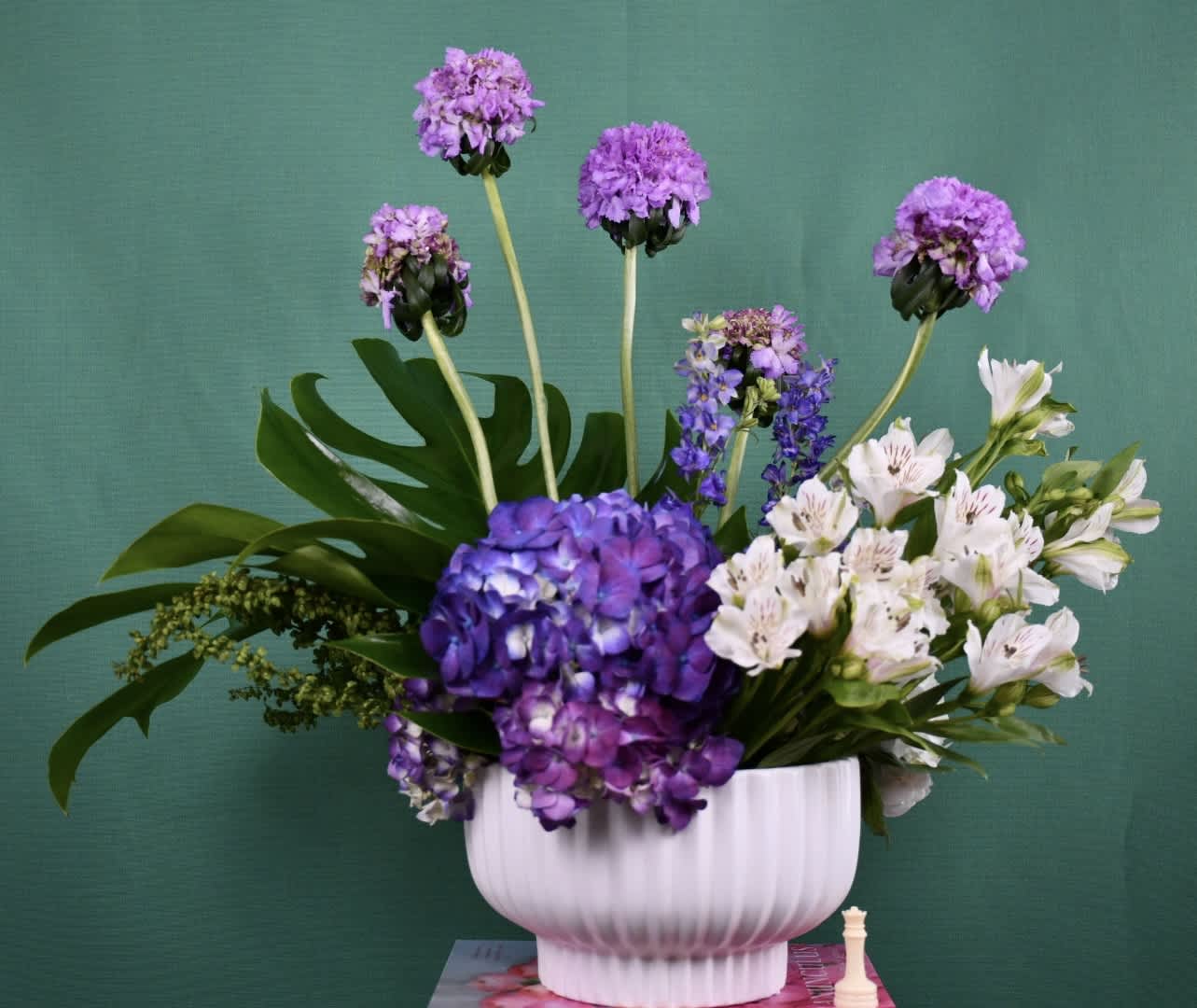 Purple and white flowers arranged in a white vase