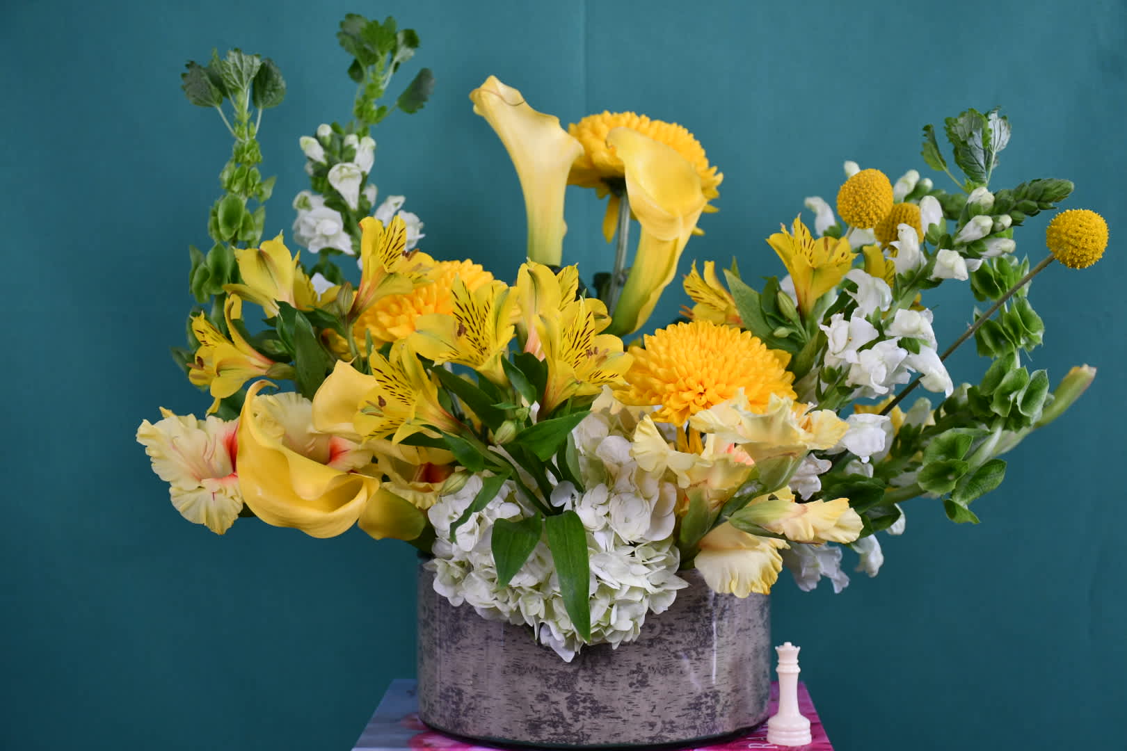 Yellow calla lilies and mixed blooms in a gray vase