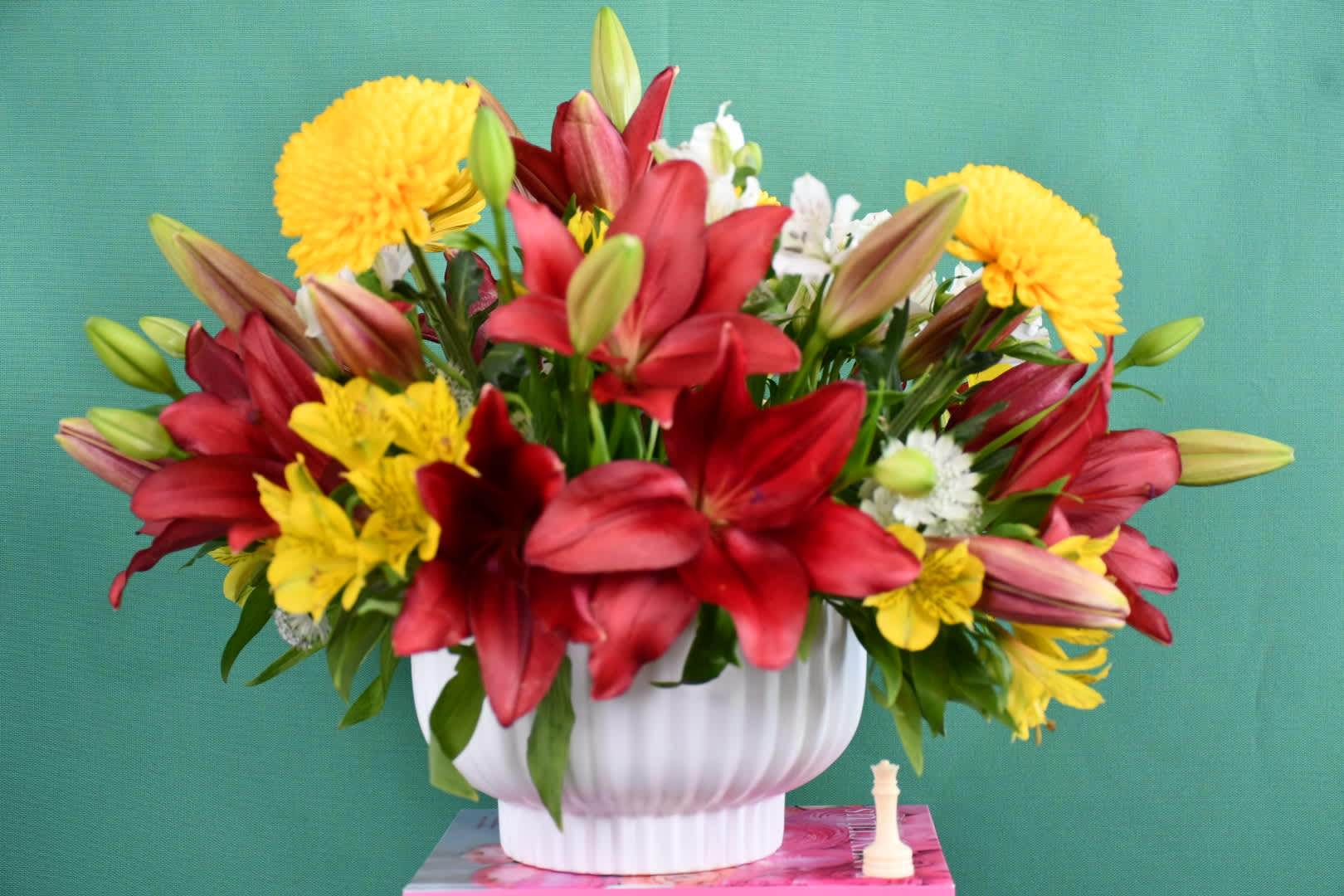 Red lilies and yellow chrysanthemums in a white vase