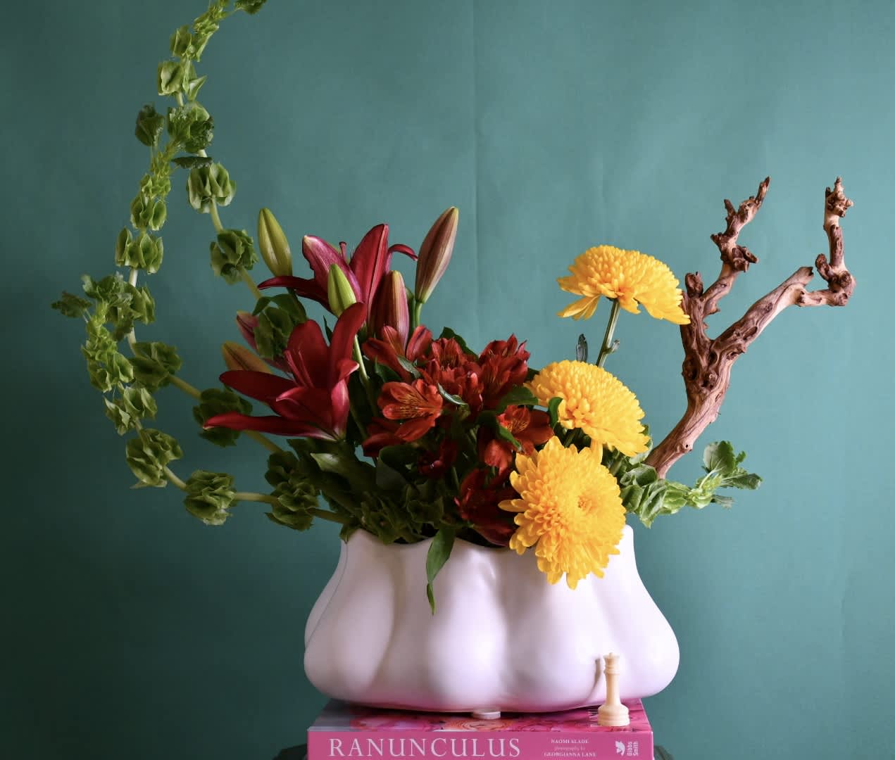 Flower arrangement in a white vase with red lilies and yellow chrysanthemums