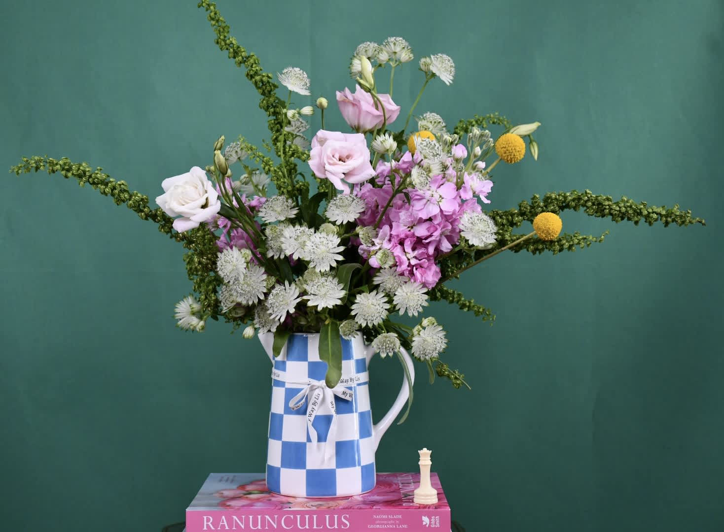 Mixed bouquet of pink and white flowers in a blue-and-white checkered pitcher