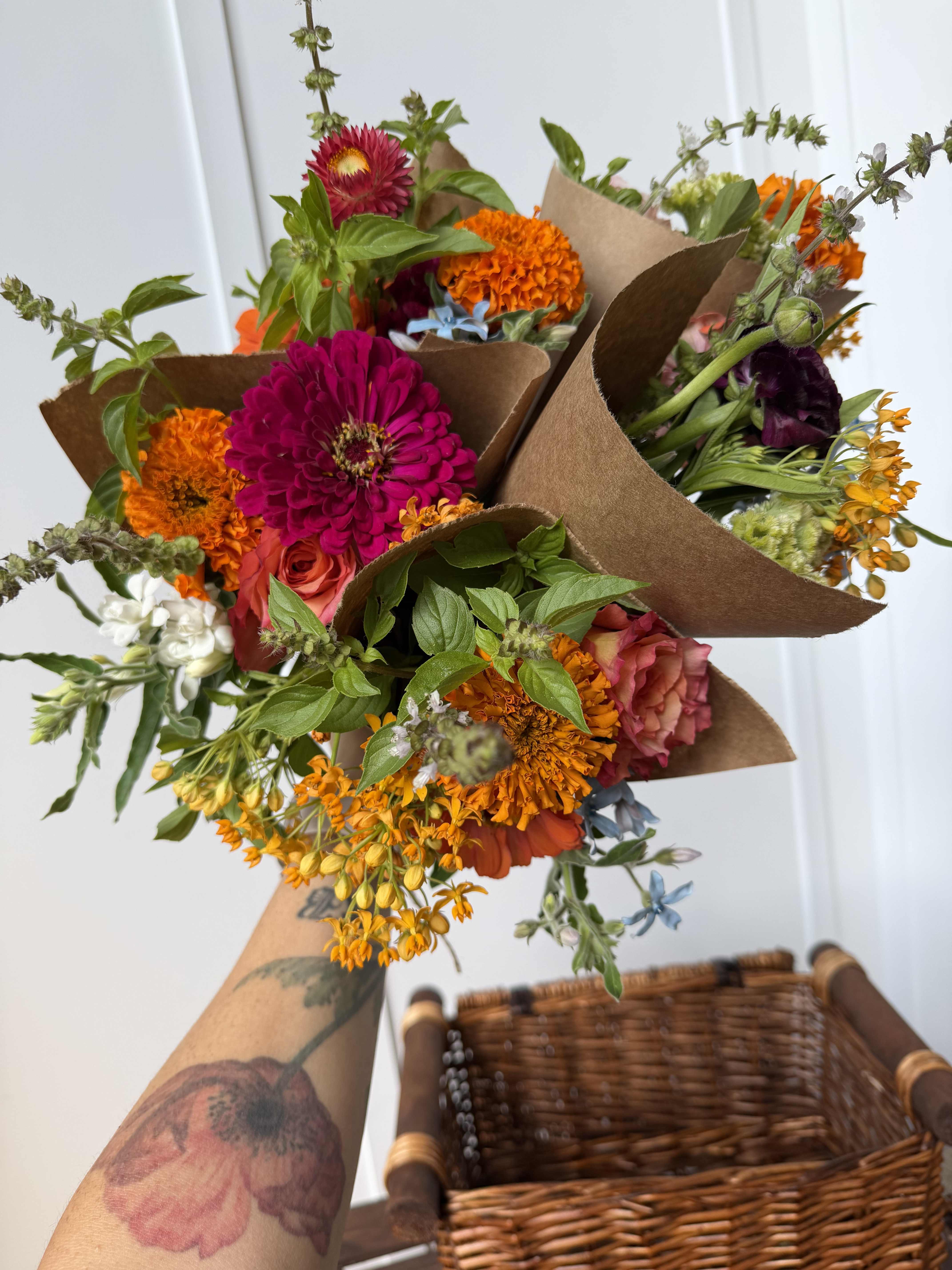 Handheld bouquets of bright mixed flowers wrapped in brown paper