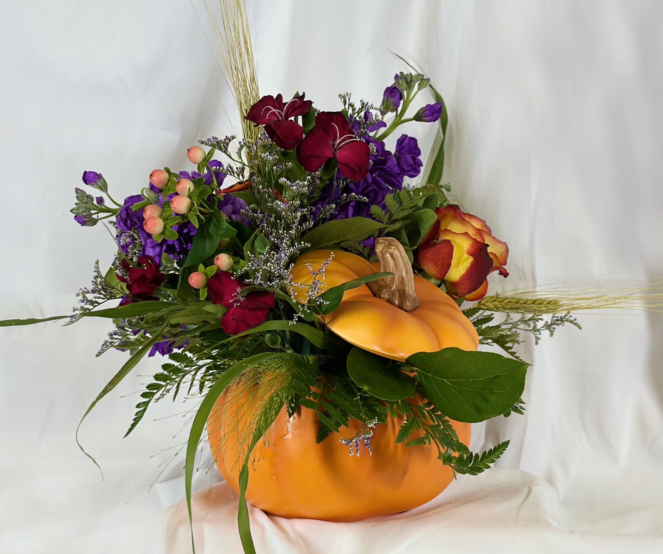 Orange Pumpkin Magic - This delightful arrangement for fall will be a perfect gift right up through Thanksgiving. bThe fall vibes transcend Halloween with purple stock, colorful roses, and more seasonal flowers.