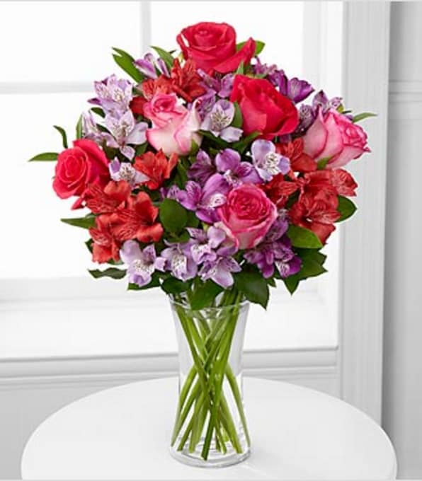 Romancing the Heart Bouquet - VASE INCLUDED - Picked fresh from the farm, the Romancing the Heart Bouquet blooms with an exceptional array of blushing color to create that perfect romantic moment! Purple, lavender, and red Peruvian Lilies create a cloud of blossoming affection surrounding pink and hot pink roses, accented with lush greens to make an unforgettable flower arrangement. This mixed flower bouquet is an excellent way to convey your heartfelt message of love to your special someone. GOOD Bouquet includes 14 stems with vase. Approximately 19"H x 15"W. BETTER Bouquet includes 20 stems with vase. Approximately 20"H x 16"W. BEST Bouquet includes 26 stems with vase. Approximately 21"H x 17"W. Your purchase includes a complimentary personalized gift message.