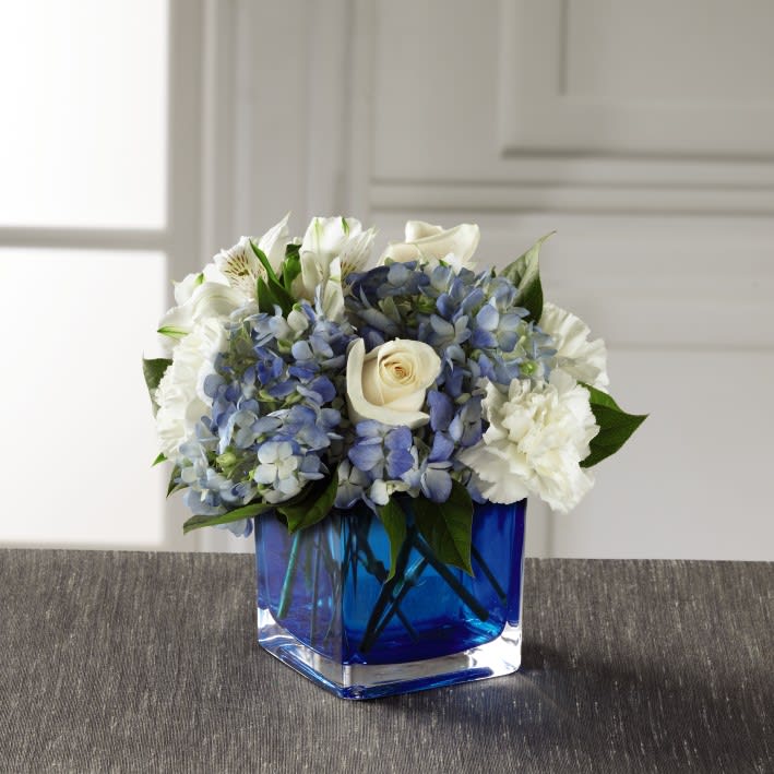 Peace &amp; Light Bouquet - A soft, charming, and stylish flower bouquet, this arrangement exudes warmth and light in celebration of Hanukkah helping you celebrate with those recipient's close to your heart. Clouds of blue hydrangea standout amongst the clean white of roses, carnations, and Peruvian Lilies accented with lush greens while seated in a modern blue glass cubed vase. A memorable way to spread peace, light, and love throughout the this festive holiday season! 