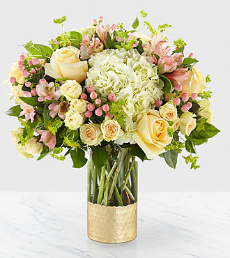 Bouquet of cream and pink flowers in a gold vase
