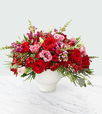 Red and pink rose arrangement in a white vase