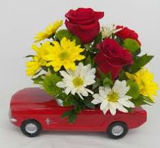 Red roses and yellow-white daisies arranged in a red toy car