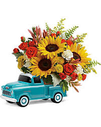 Bouquet of sunflowers and red roses in a turquoise toy truck
