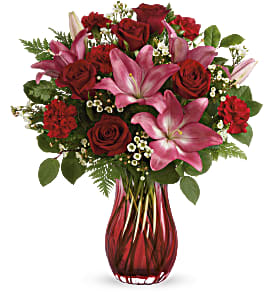 Red roses and pink lilies in a red glass vase