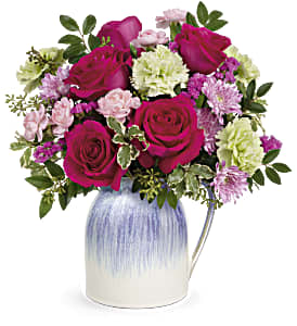 Bouquet of magenta roses and pastel carnations in a blue-and-white vase