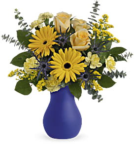 Yellow and cream flower arrangement in a blue vase