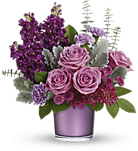Purple roses and mixed blooms in a lavender glass vase
