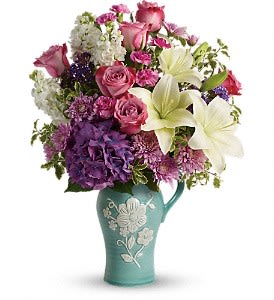 Mixed bouquet of pink, purple, and white flowers in a teal vase