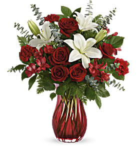 Red roses and white lilies in a red glass vase