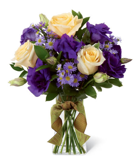 Angelique Bouquet - Angelique Bouquet blooms with sweet sophistication and gorgeous grace to create a special moment for your recipient. Cream roses are arranged to perfection against the royal purple hues of double lisianthus and monte casino asters perfectly accented with lush greens. Presented in a clear gathered square glass vase tied at the neck with an amber wired taffeta ribbon, this bouquet is an exquisite way to extend your warmest wishes and affection. GOOD bouquet includes 9 stems.  BETTER bouquet incudes 15 stems.. BEST bouquet includes 19 stems.