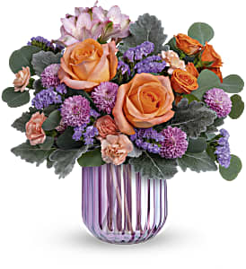 Orange roses and purple flowers in a striped glass vase