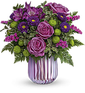 Purple roses and mixed purple flowers in a striped glass vase