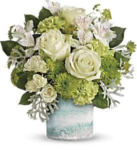 White roses and green flowers arranged in a glass vase
