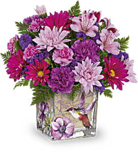 Pink and purple mixed bouquet in a square glass vase with a hummingbird design