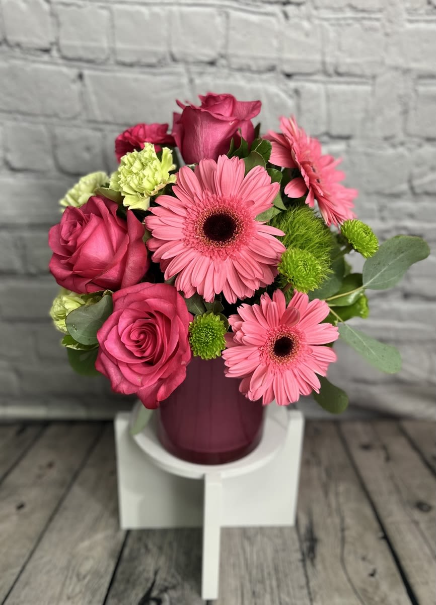 Pink roses and gerbera daisies arranged in a purple vase
