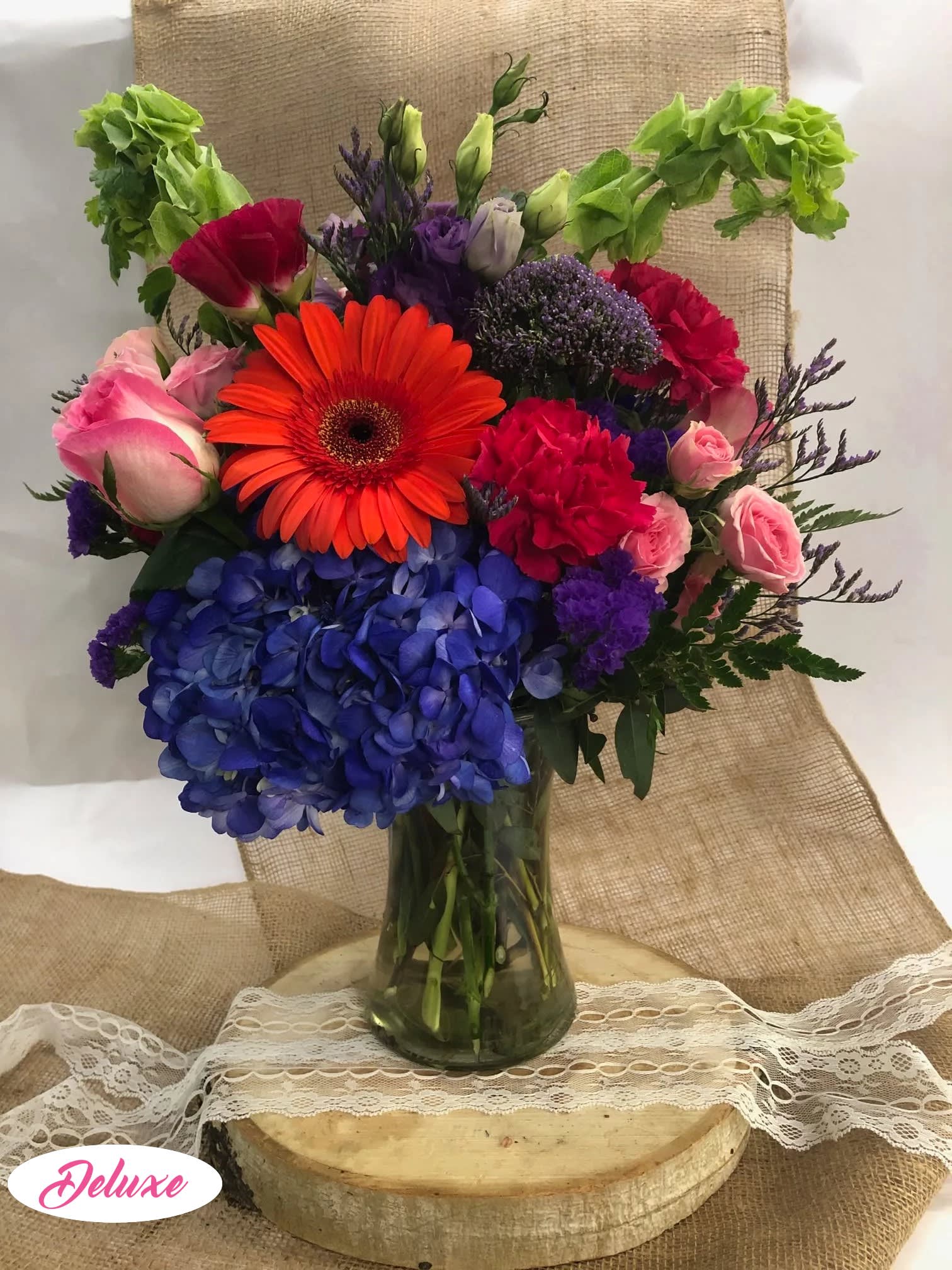 Colorful mixed bouquet in a glass vase with hydrangeas, roses, and a gerbera daisy