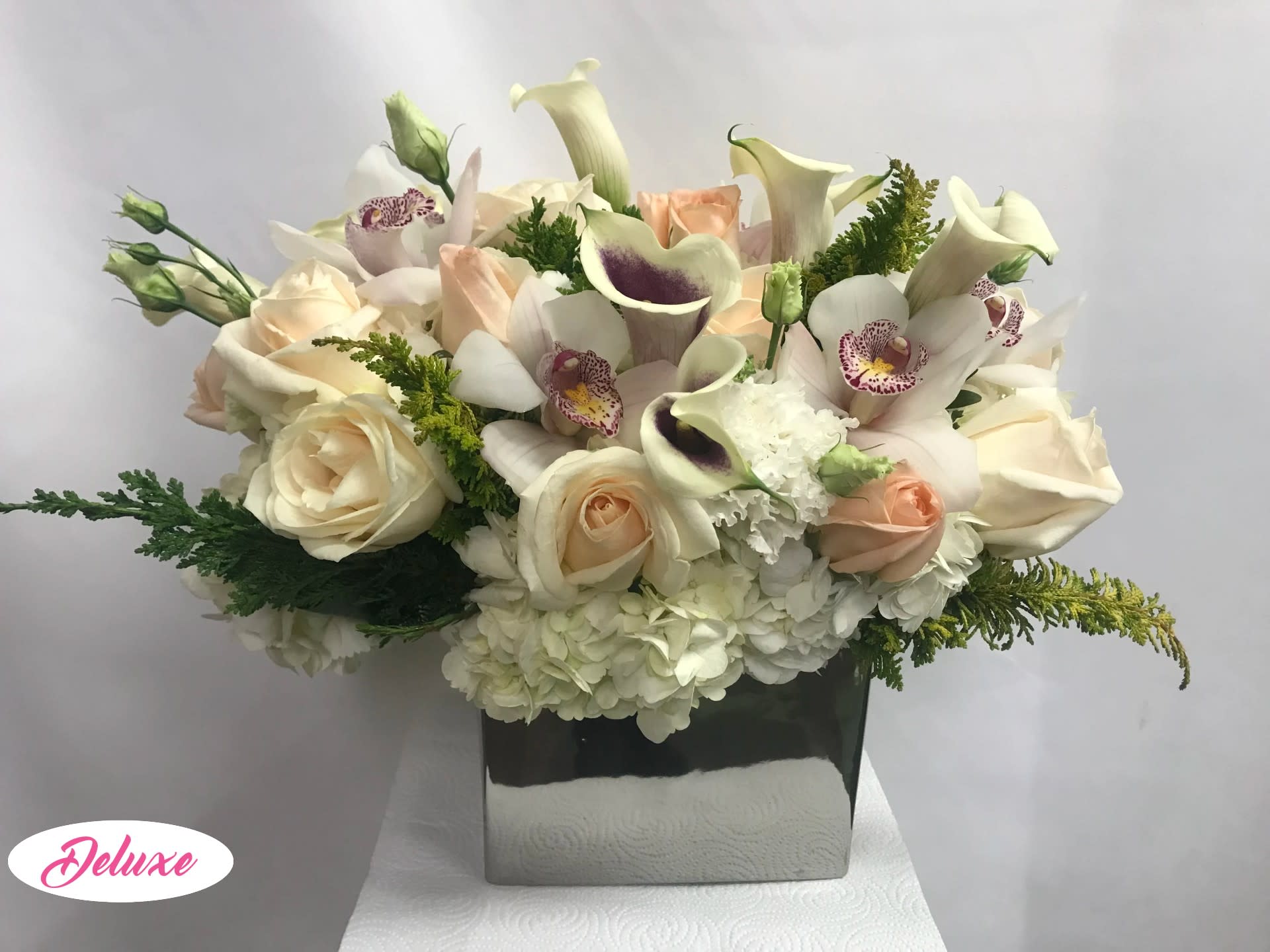 Cream roses and calla lilies in a square vase
