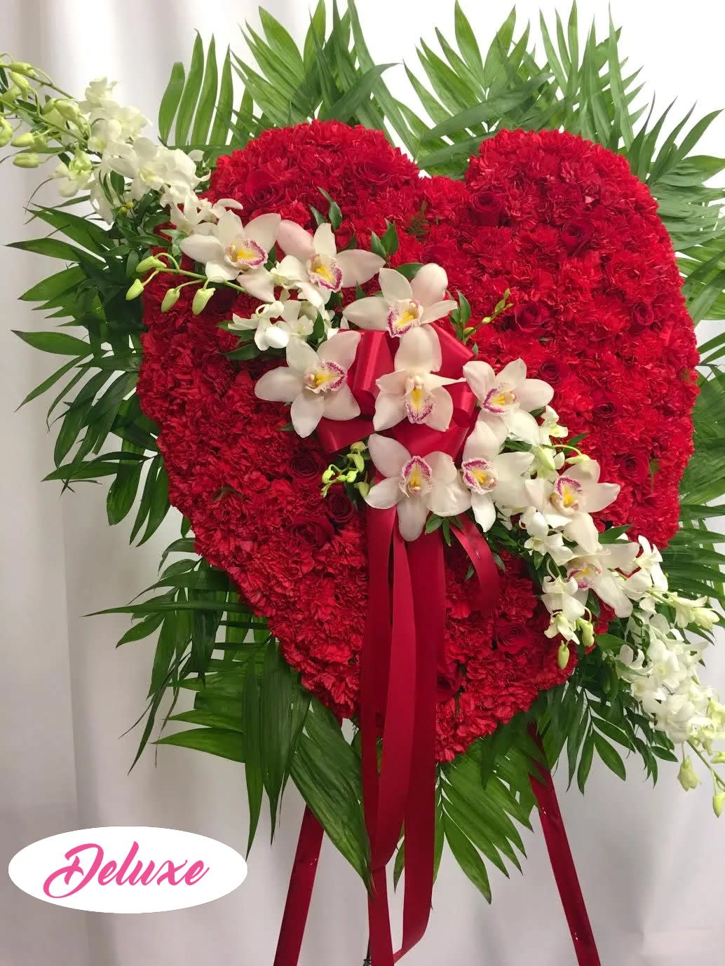 Heart-shaped red floral standing spray with white orchids and ribbon