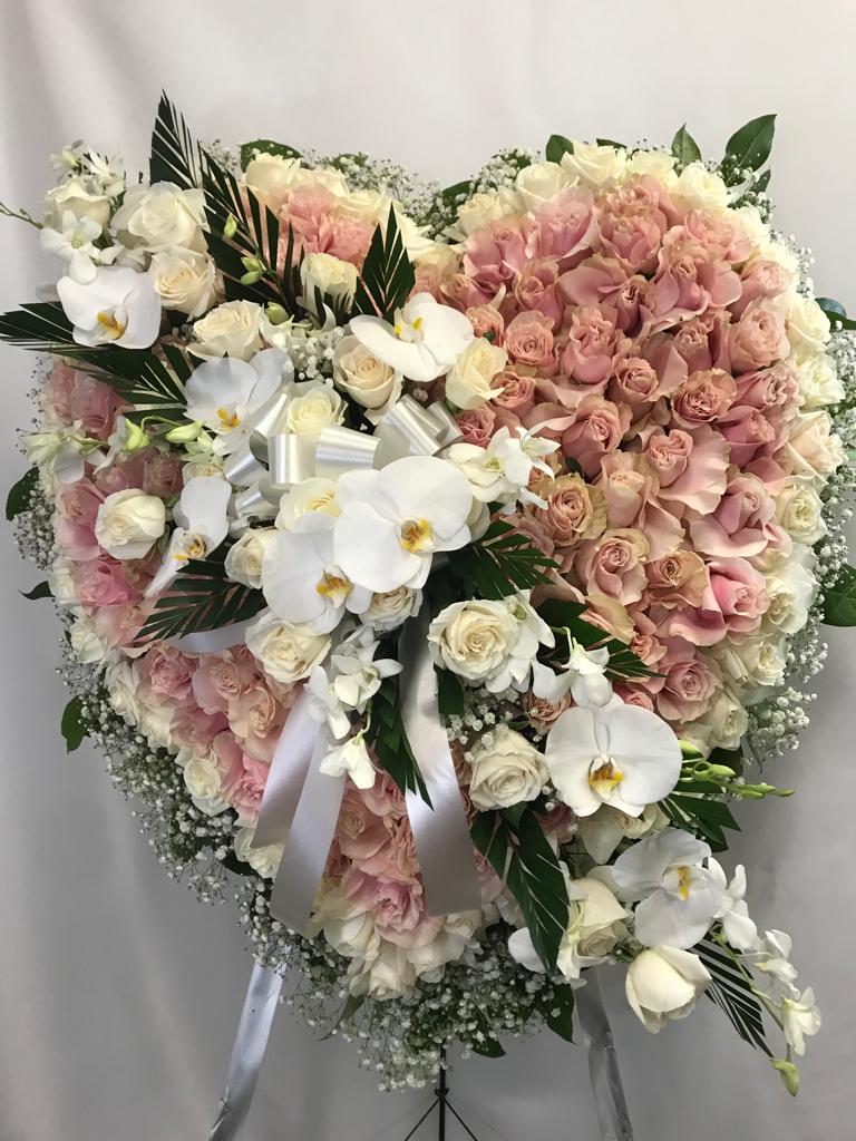 Heart-shaped bouquet of pink and white roses with orchids and ribbon