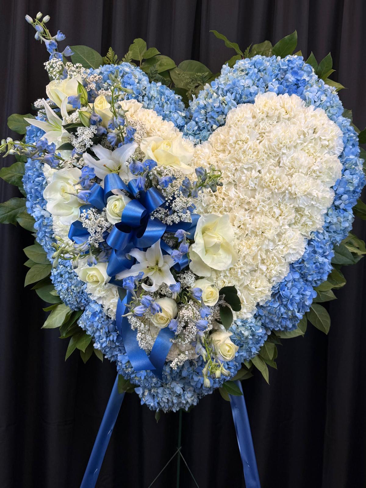 Heart-shaped blue and white floral standing spray with ribbon