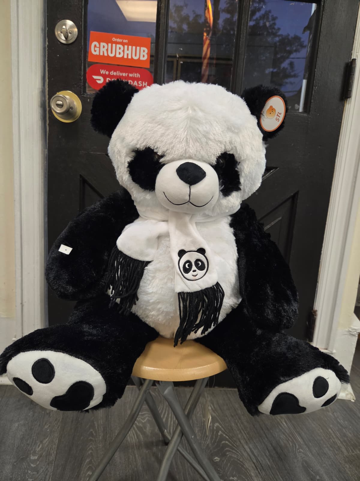 Large black-and-white panda plush toy sitting on a stool