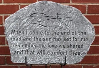 A painted memorial stone with a quote on a brick wall