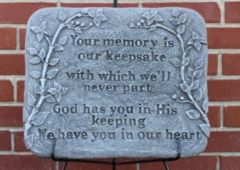 Memorial plaque with engraved text and vine border on a brick wall