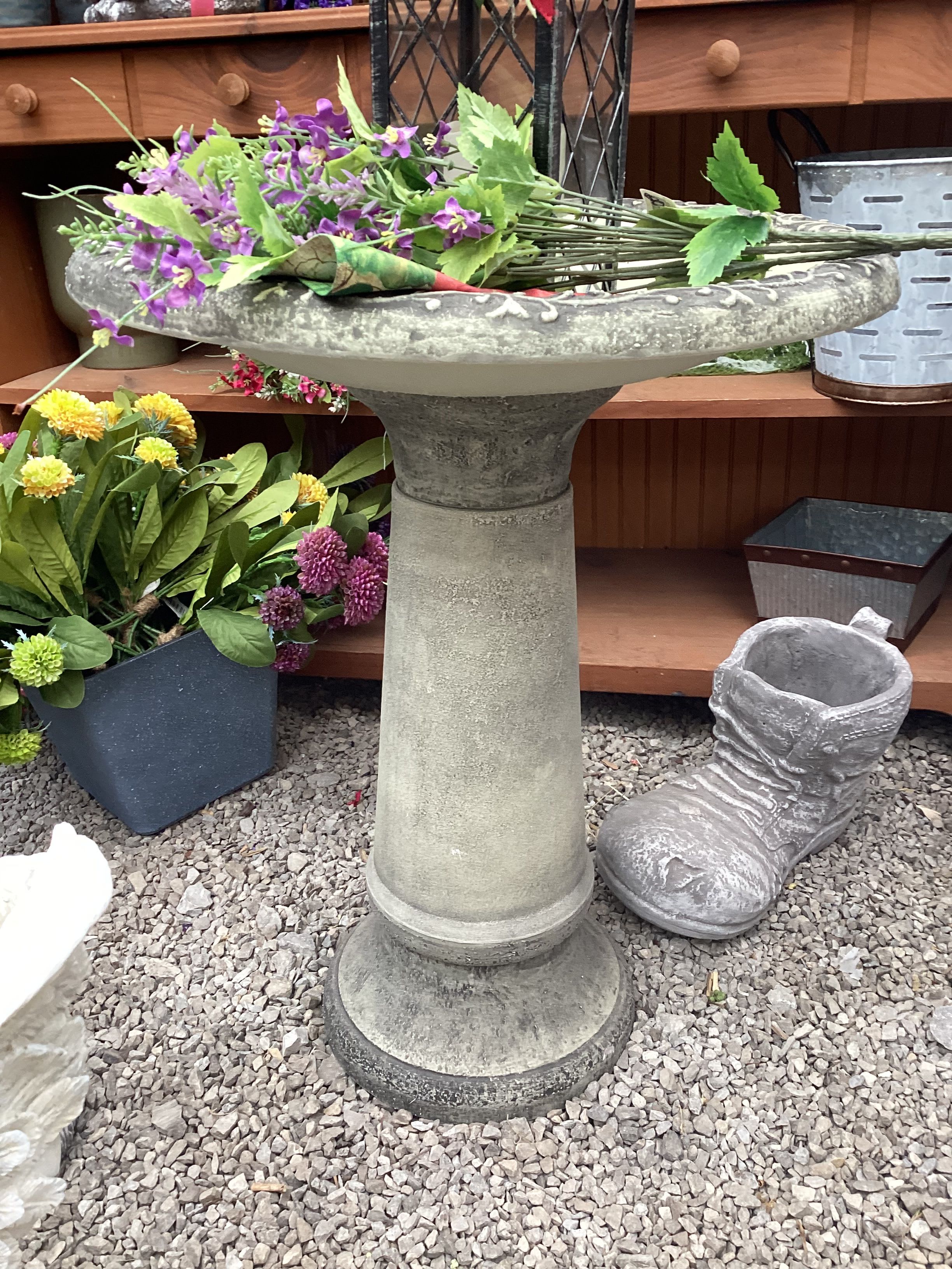 Purple flowers arranged in a stone birdbath planter