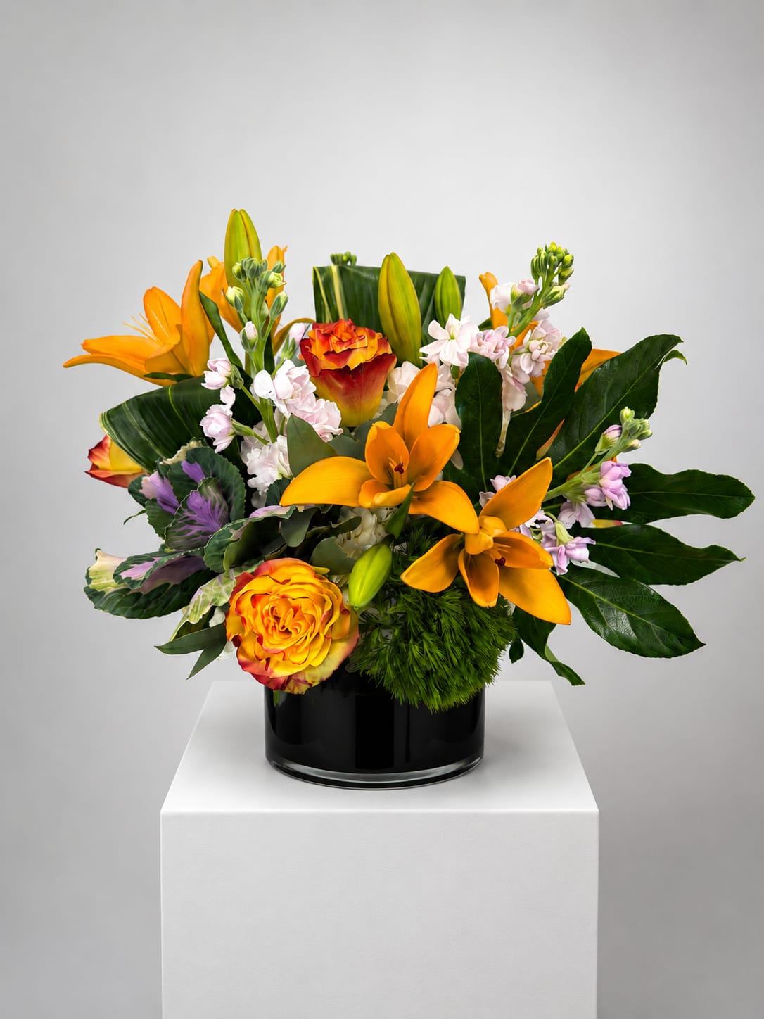 Orange lilies and roses arranged in a black vase