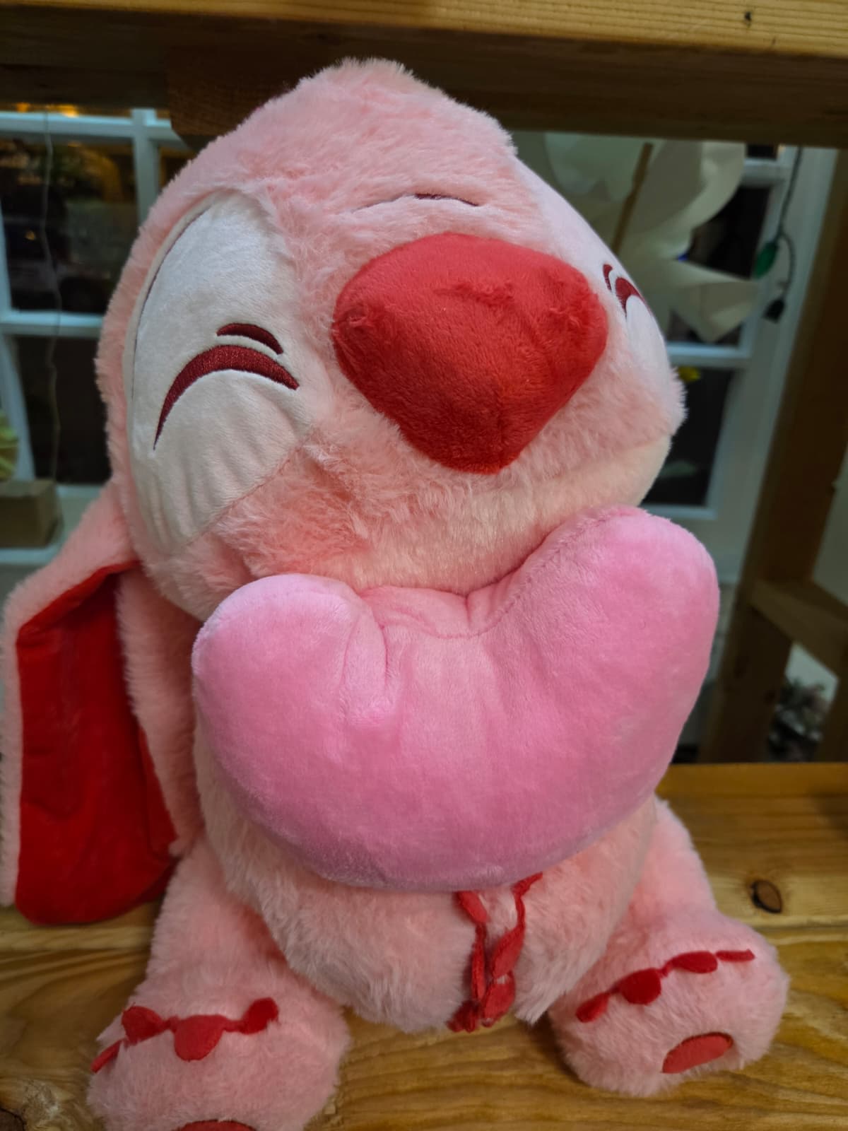 Pink plush teddy bear holding a heart pillow