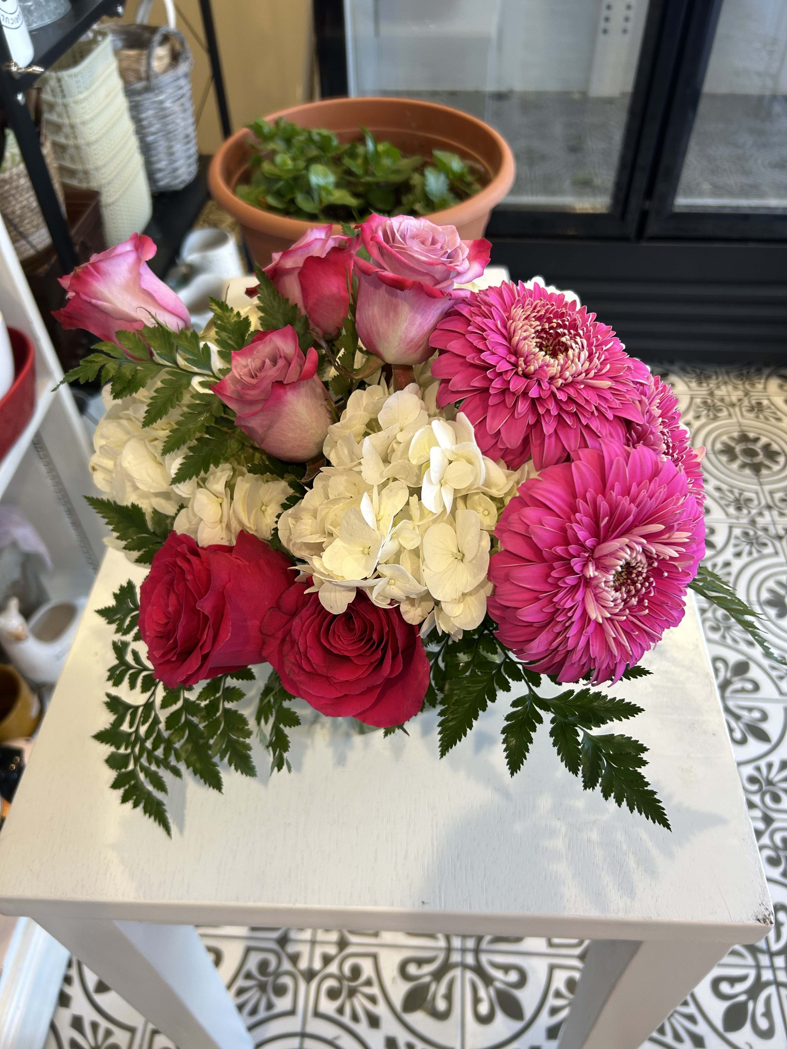 Pink roses and bright pink gerbera daisies with white hydrangea in a low bouquet