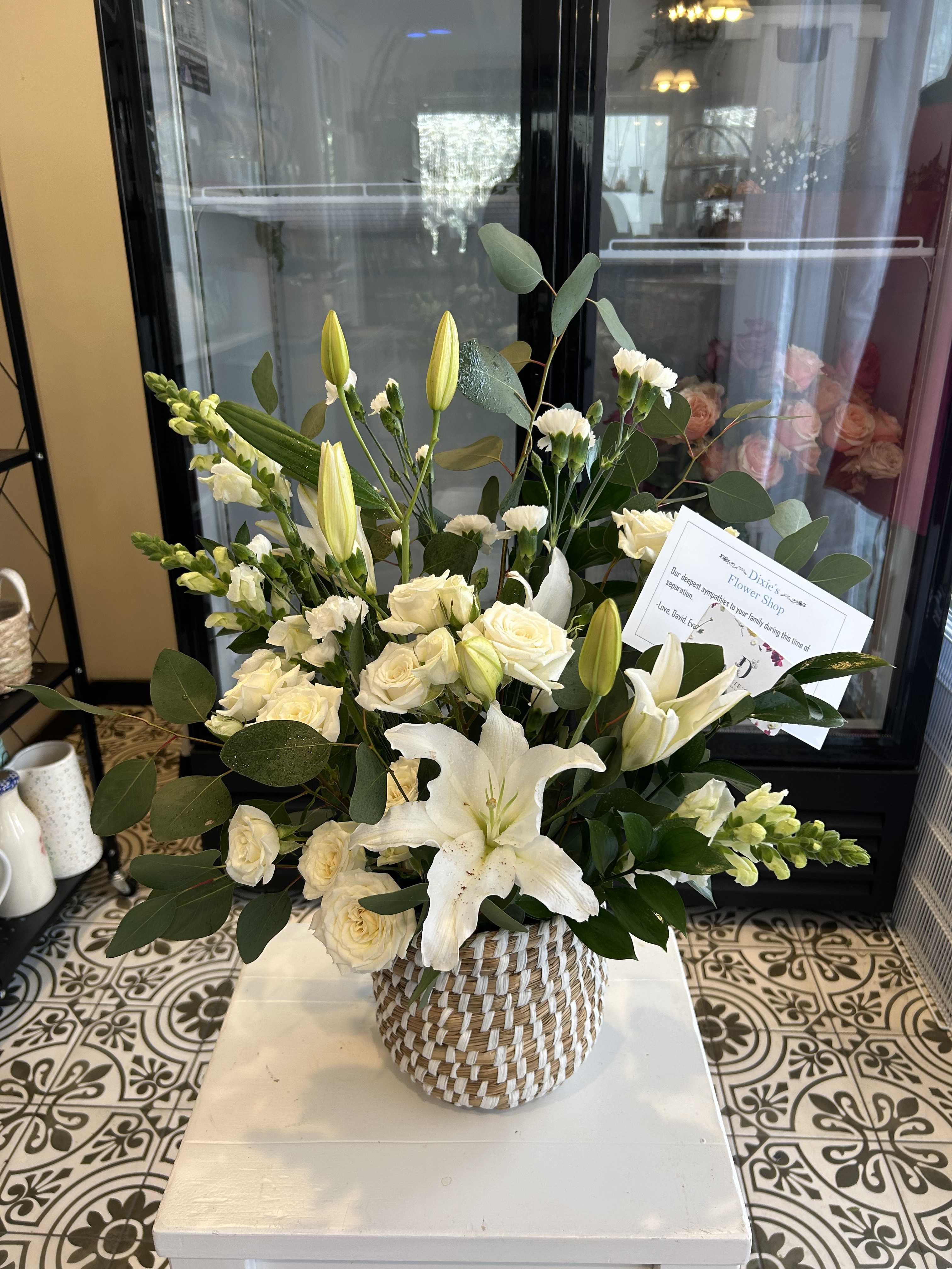 White lilies and cream roses arranged in a woven basket
