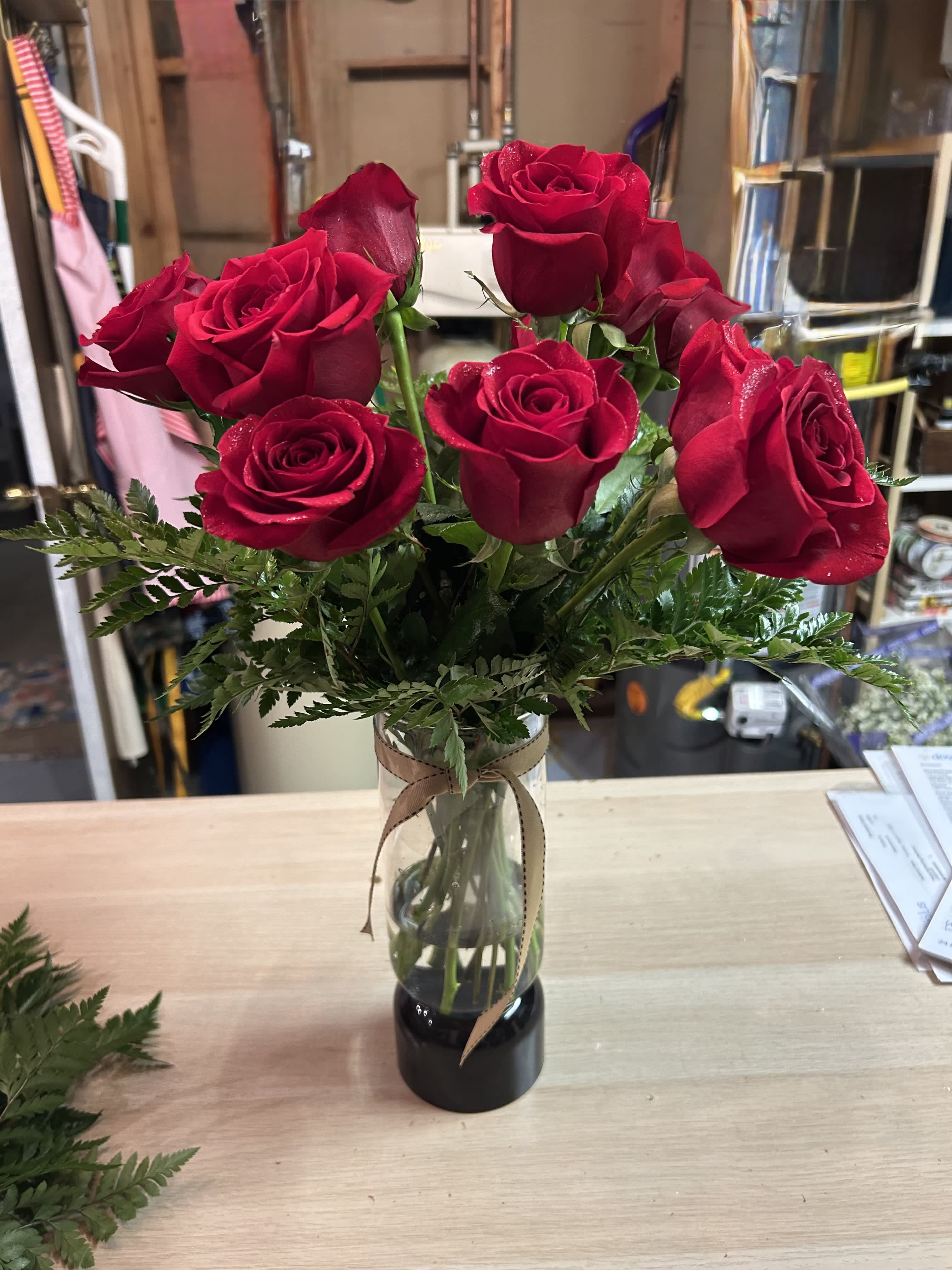Red roses arranged in a clear glass vase with a ribbon
