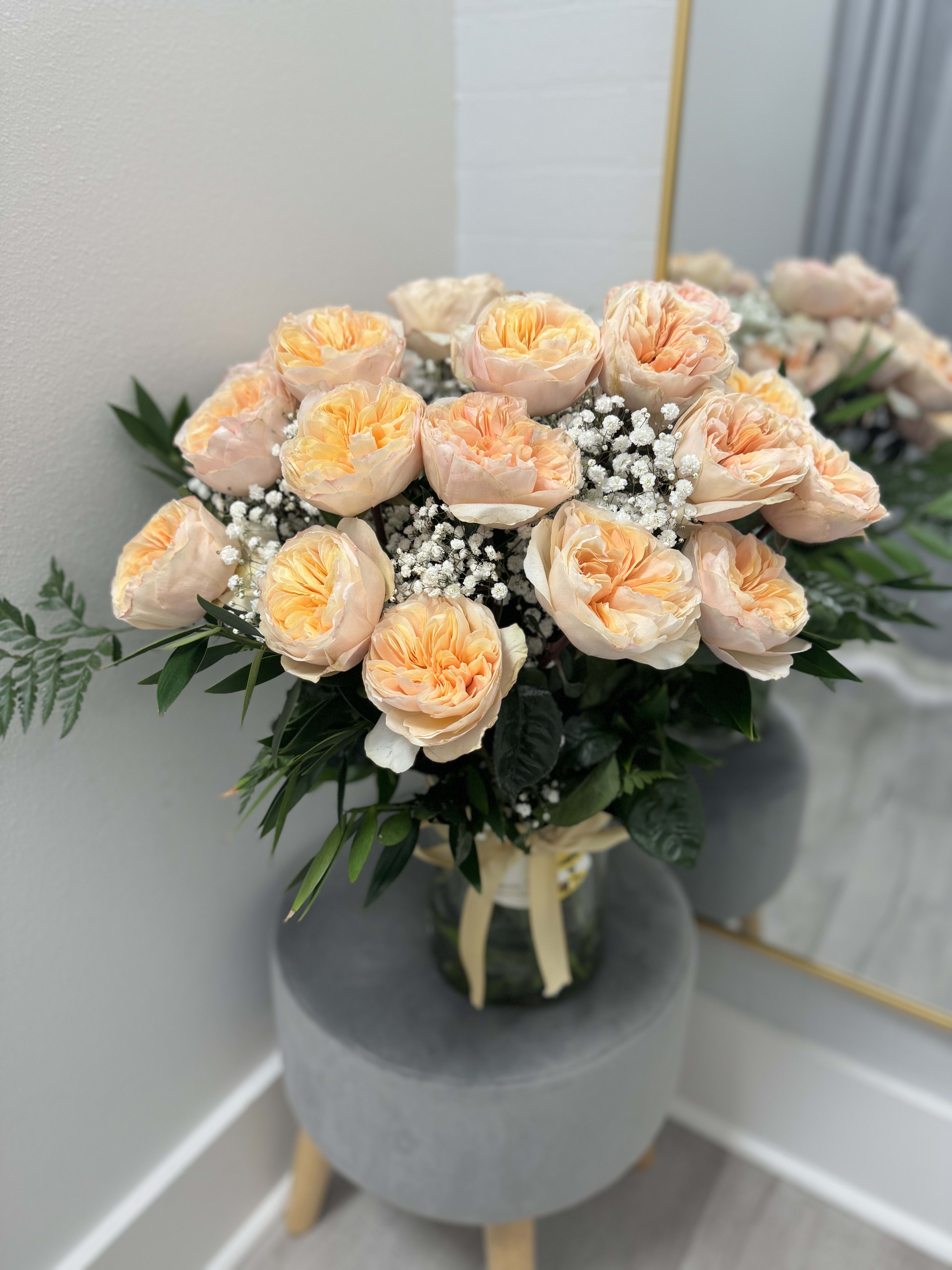 Divine Pink Garden Rose Arrangement - Elevate your floral experience with our **Divine Pink Garden Rose Arrangement**, featuring an extravagant collection of 24 large, luscious pink garden roses elegantly arranged in a beautiful vase. Each rose is a symbol of love and elegance, boasting soft petals that exude a delicate fragrance, promising to captivate anyone who encounters them.  This stunning arrangement is beautifully complemented by tender baby’s breath, vibrant greenery, and lush fern, enhancing the overall allure and creating a lush, natural vibe. The varied textures and hues come together harmoniously to form a breathtaking centerpiece, perfect for any occasion.  Wrapped with care in a soft ribbon and adorned with a charming sticker, this arrangement is ready to delight as a thoughtful gift or an exquisite addition to your home decor. Transform your space into a serene haven of beauty and elegance with this show-stopping floral display!  Bring home this stunning vase arrangement and let the magic of roses brighten your world! ??