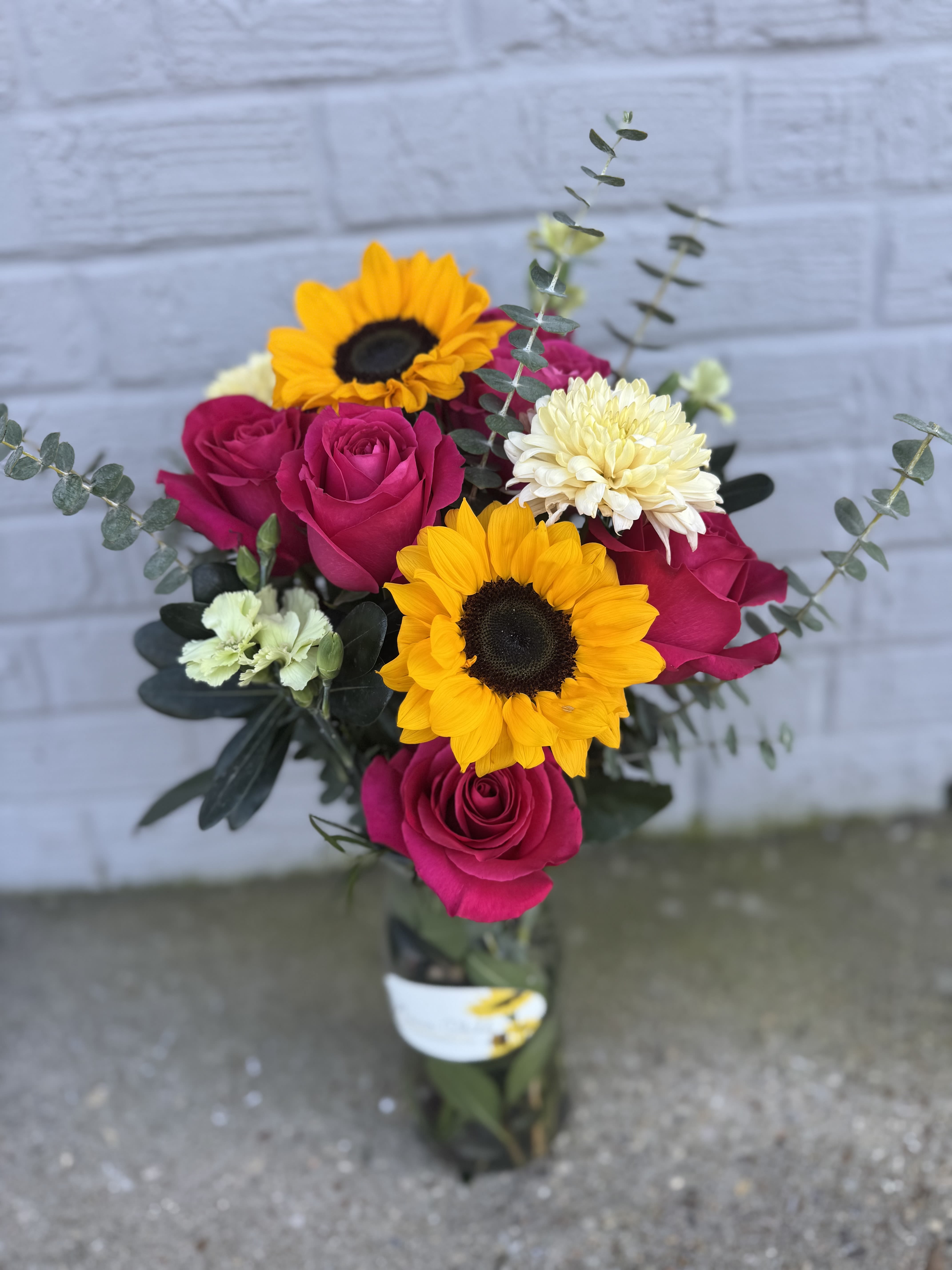 Summer Days  - Elevate any occasion with our Summer Days arrangement!  Featuring 6 vibrant roses, 2 cheerful sunflowers, and fragrant eucalyptus, filler flowers in a vase. 