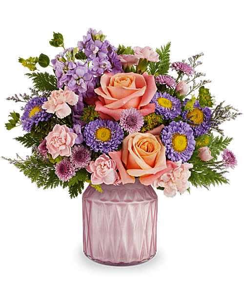 Pink and lavender flower arrangement in a mauve glass vase