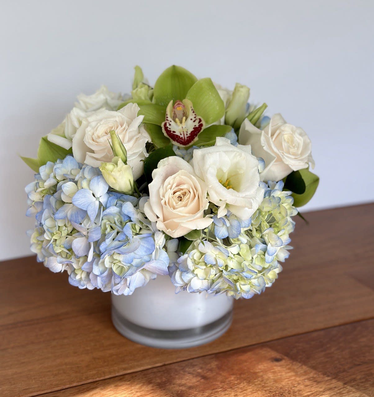 White and pale blue flowers arranged in a low glass vase